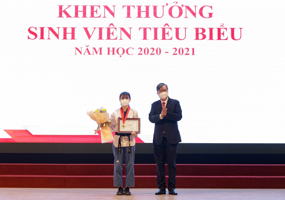 PGS.TS. Vương Đức Hoàng Quân - Bí thư Đảng ủy, Chủ tịch Hội đông trường trao giấy khen và hoa cho sinh viên Nguyễn Thị Kim Hà - Sinh viên xuất sắc Khoa Khoa học thể thao.